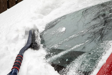 Snowdrift and brush on windshield of car. Cleaning car from snow. Concept of bad weather, snow storm