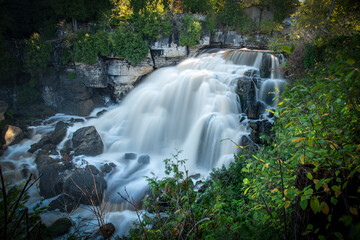 The milky waters of Inglis Falls near Owen Sound, Ontario flow down over the rocks and through the surrounding forest.