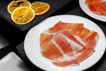 Sliced ham in thin slices lies on a plate.