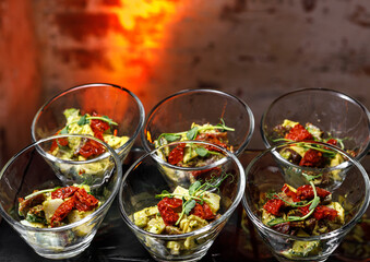 A light snack of potatoes, cucumbers, chili peppers, chicken meat and herbs in transparent serving cups.