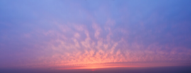 Sunset sky background with beautiful clouds. Panoramic view of evening sky.