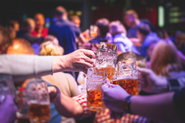 View of beer festival, gold coloured beer glasses assortment in a pub, german unfiltered wheat beer, people cheering up and toasting with glasses of light lager, Oktoberfest view