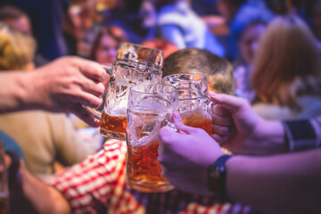 View of beer festival, gold coloured beer glasses assortment in a pub, german unfiltered wheat beer, people cheering up and toasting with glasses of light lager, Oktoberfest view