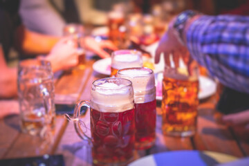 View of beer festival, gold coloured beer glasses assortment in a pub, german unfiltered wheat beer, people cheering up and toasting with glasses of light lager, Oktoberfest view
