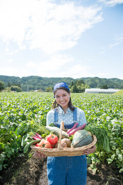 畑で収穫した野菜を見せる女性