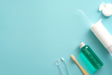 Oral water irrigator, toothbrush, dental floss on blue background. Dental clinic banner design. Flat lay, top view, copy space.