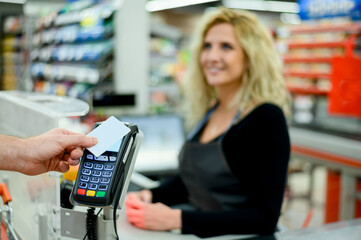 Mans hand making a contactless payment with his credit card at a supermarket