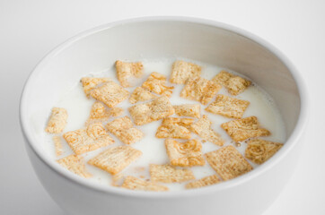 Yummy breakfast. Cinnamon cereal, healthy breakfast meal. Cereal squares in bowl isolated on white background.