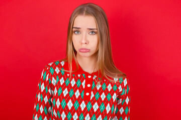 Young beautiful caucasian girl wearing christmas sweaters on red background depressed and worry for distress, crying angry and afraid. Sad expression.