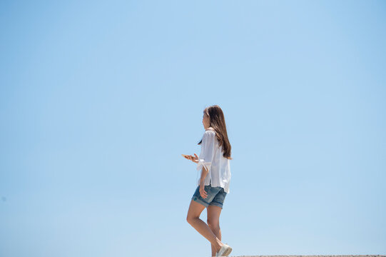 海の堤防を歩いてスマホで音楽を聴く女性