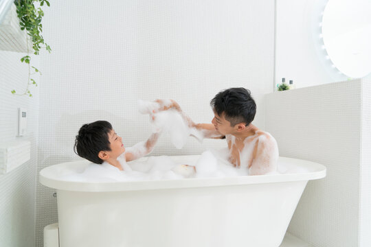 お風呂に入って泡で遊ぶ父と息子