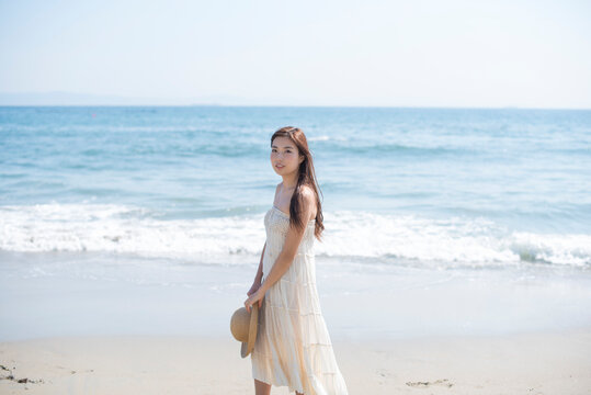 海の砂浜を素足で散歩する女性