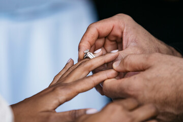 Obraz na płótnie Canvas Groom putting on wedding ring on bride finger