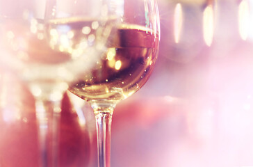 Glasses of wine on pink bokeh background.