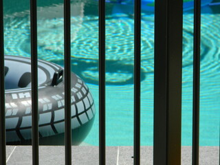 Close up of a swimming pool and floatie behind a black pool safe fence