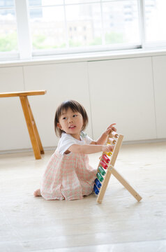 部屋の中で100玉そろばんで遊ぶ女の子