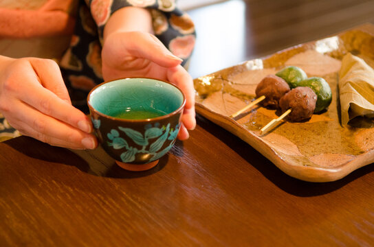 机にある和菓子と湯のみに添えられた着物姿の女性の手