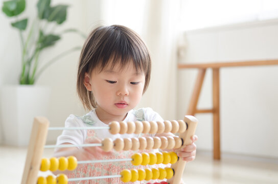 部屋の中で100玉そろばんで遊ぶ女の子