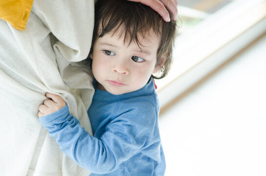 お母さんの足にしがみつく男の子