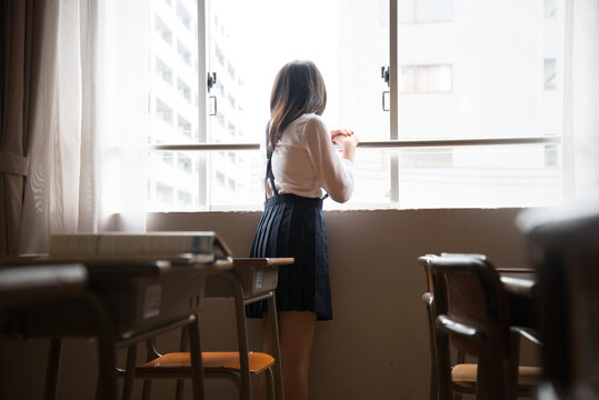 教室の窓の外を見ている小学生の女の子