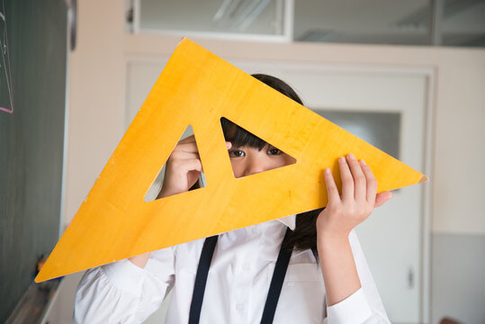 黒板の前で三角定規を持っている小学生の女の子