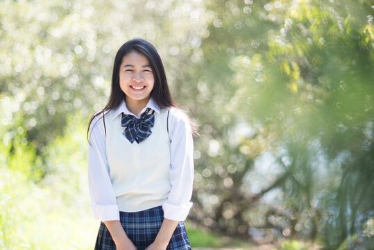 緑の中で笑っている制服姿の女子高生