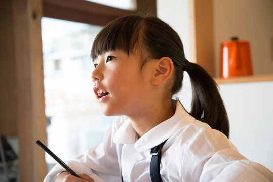 鉛筆を持って話している制服姿の女の子