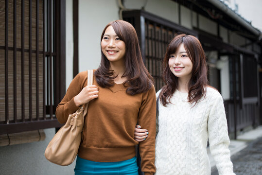 町屋の前に立っている女性2人