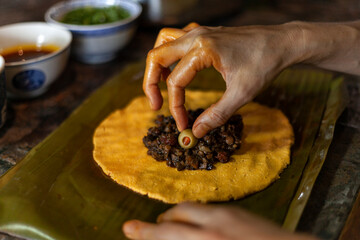 Close up of hands preparing hallaca or tamale. Traditional food concept