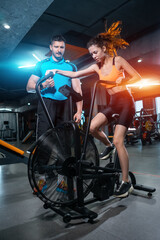 Fototapeta na wymiar female has workout and training on exercise bike with personal trainer in gym