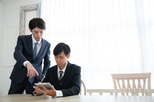 タブレットを使い説明を受けるスーツ姿の男性