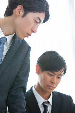 男性から説明を受けるスーツ姿の男性