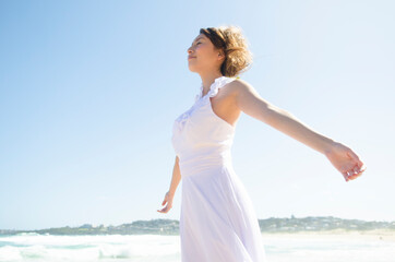 ビーチで両手を広げているドレス姿の女性
