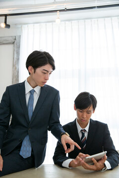 タブレットを使い説明を受けるスーツ姿の男性