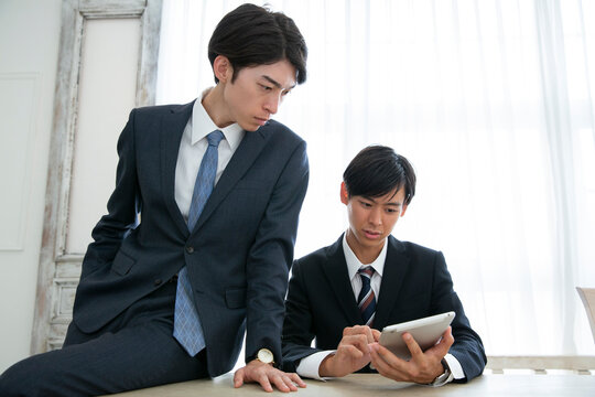 タブレットを使い説明を受けるスーツ姿の男性