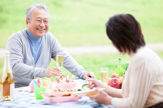 屋外で食事しながら笑顔で会話する中高年夫婦