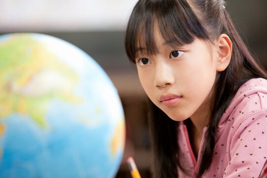 地球儀を見ている小学生の女の子 - Powered by Adobe