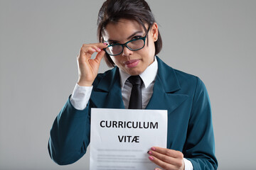 Businesswoman holding CV lowering her glasses to look at camera