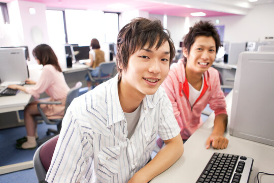 パソコンの前に座っている男子大学生2人