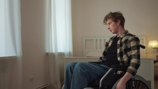 A young disabled man is riding in his wheelchair around the room