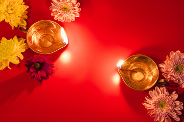 Happy Diwali. Traditional Hindu celebration. Diya oil lamps and flowers on red background. Religious holiday of light.