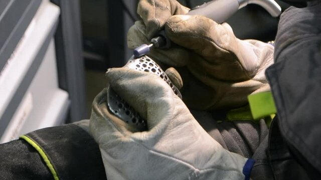 Worker grinding metal detail close-up. Person in working gloves manually