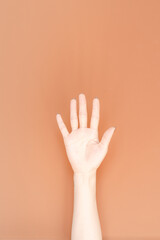 hand showing number five In front of the brown background,