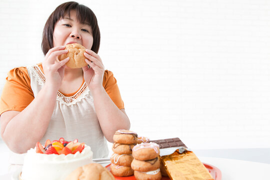 シュークリームを食べる肥満女性