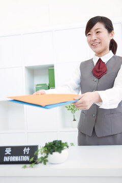 ファイルを差し出す受付の女性
