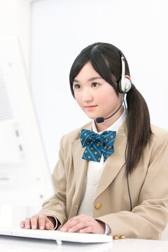 インカムをつけてパソコンをする女子高生