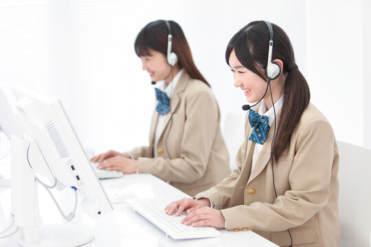 インカムをつけてパソコンをする女子高生2人