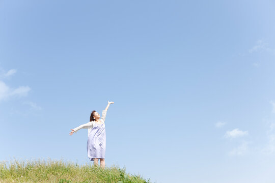 空を見上げて腕を広げる女性