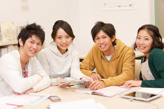 勉強する笑顔の大学生4人