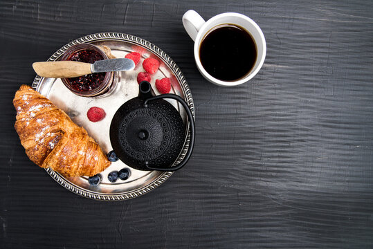 Cup of Coffee and croissants with jam for breakfast on bleck table.